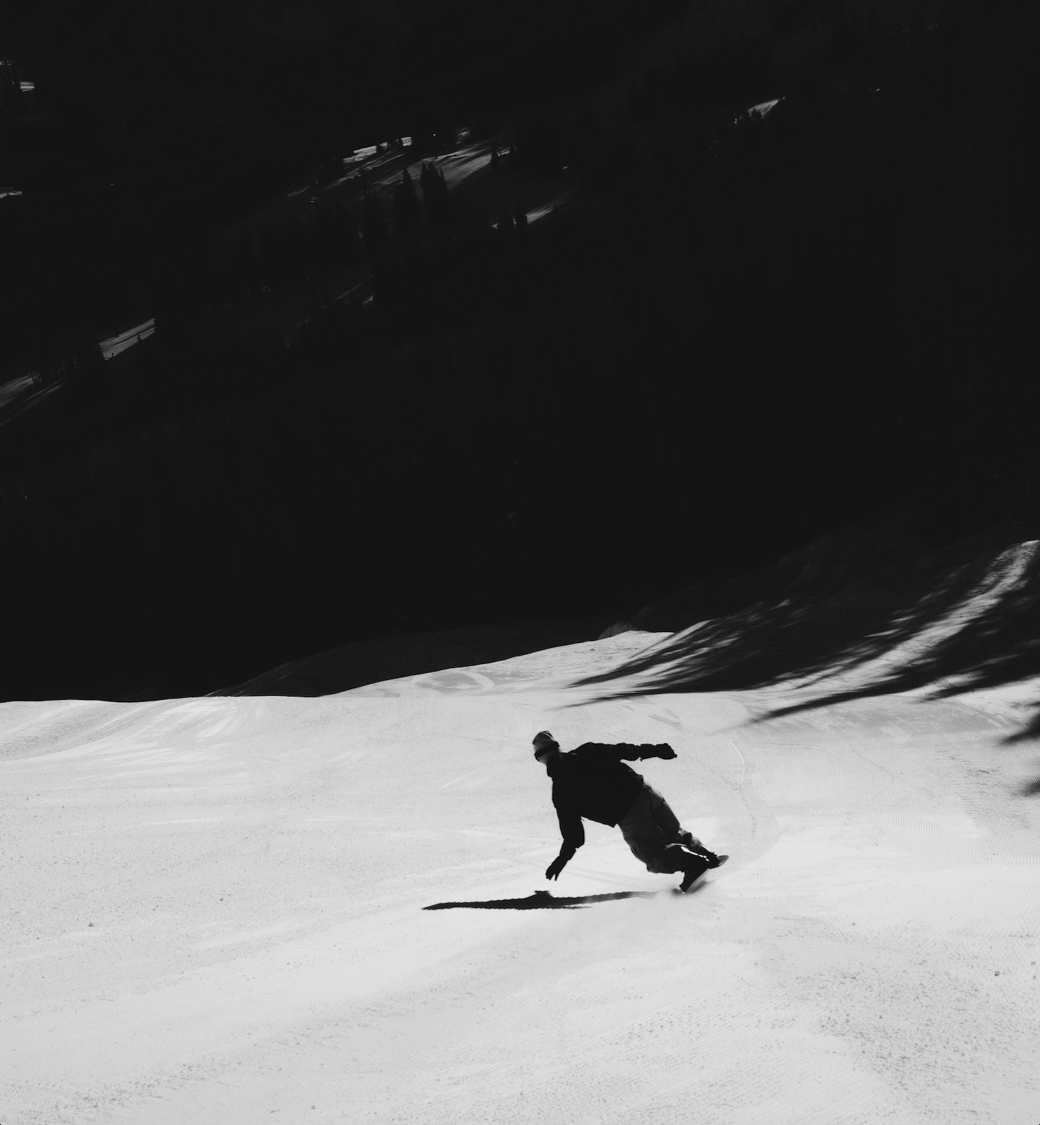 Person snowboarding down a snowy slope with a dark background